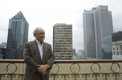 David Azrieli standing in front of three skyscrapers.