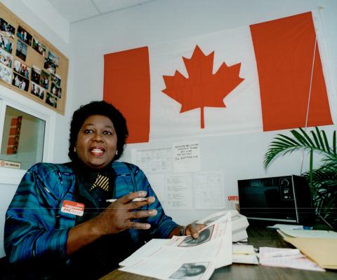 Jean Augustine at a desk in front of a Canadian flag.