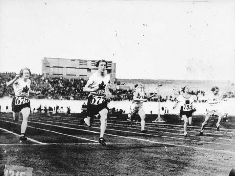 Black and white image of Bobbie Rosenfeld and four women running race around a track.