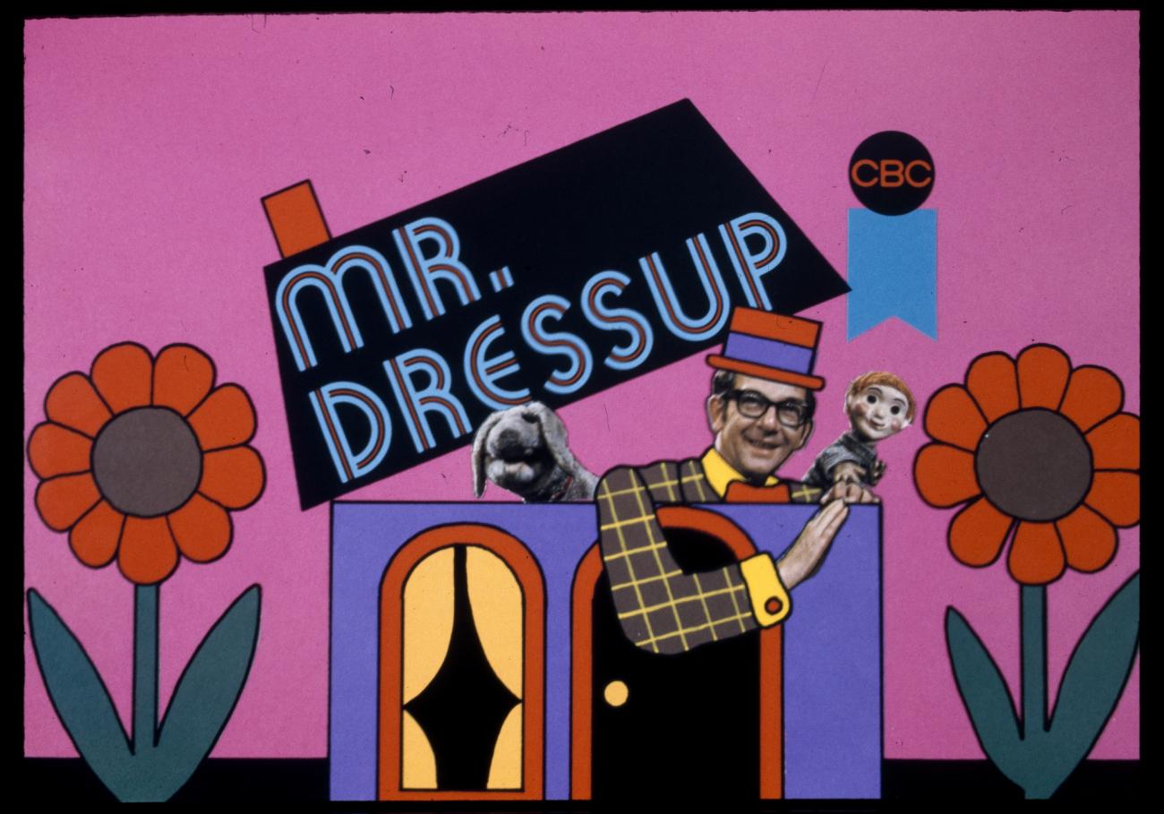 a colourful graphic of a house and flowers, with Ernie Coombs' Mr Dressup and two puppets.
