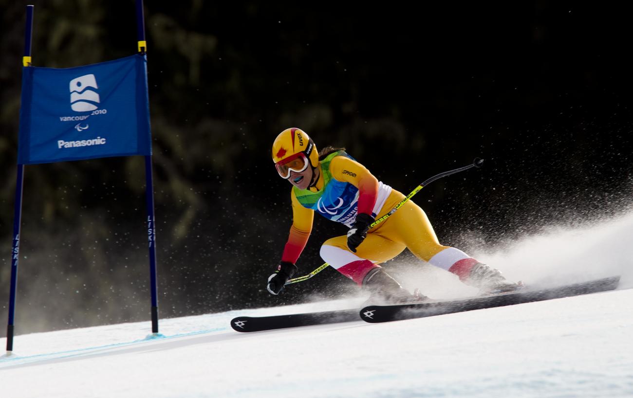 Karolina Wisniewska dressed in yellow skiing towards a blue flag.