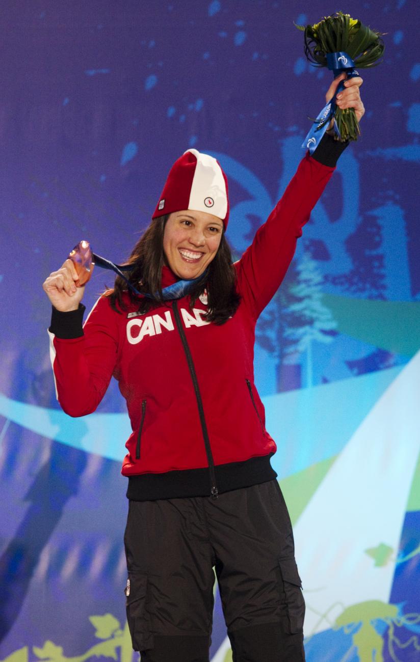 Karolina Wisniewska in a red Canada jacket and hat holds up a medal.
