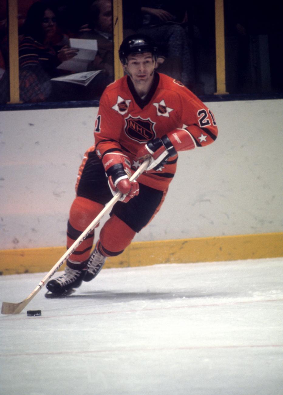 Stan Mikita in red uniform skating holding a hockey stick.