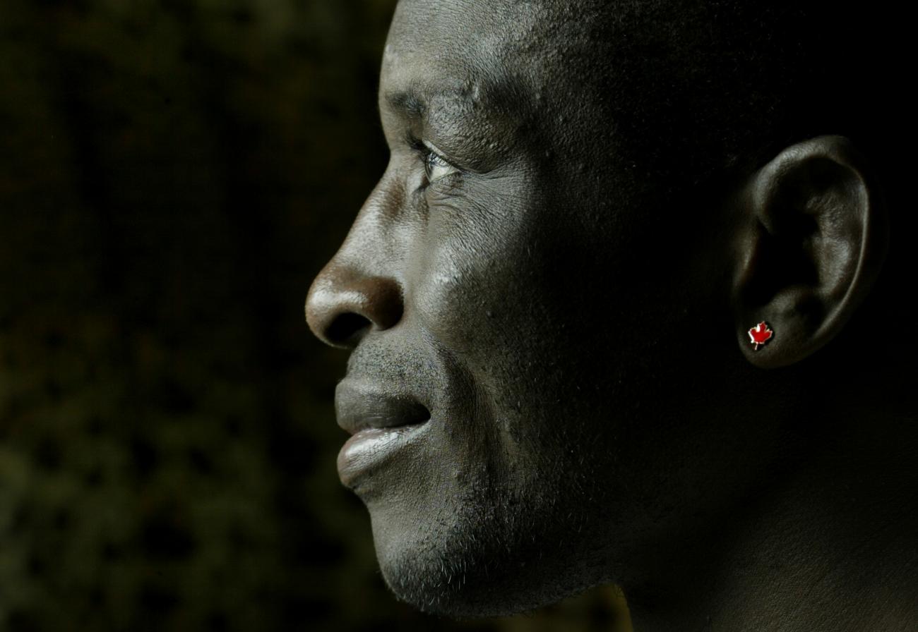 close-up profile of Daniel Igali wearing a red Canada maple leaf earring.