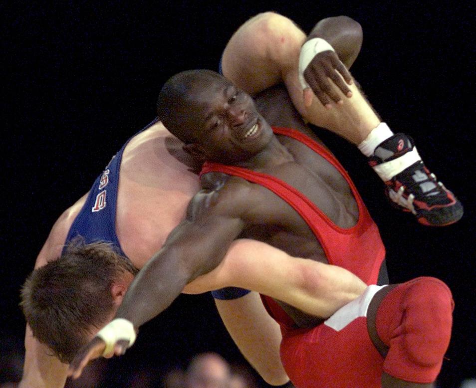 Daniel Igali in a red costume wrestling with another man.