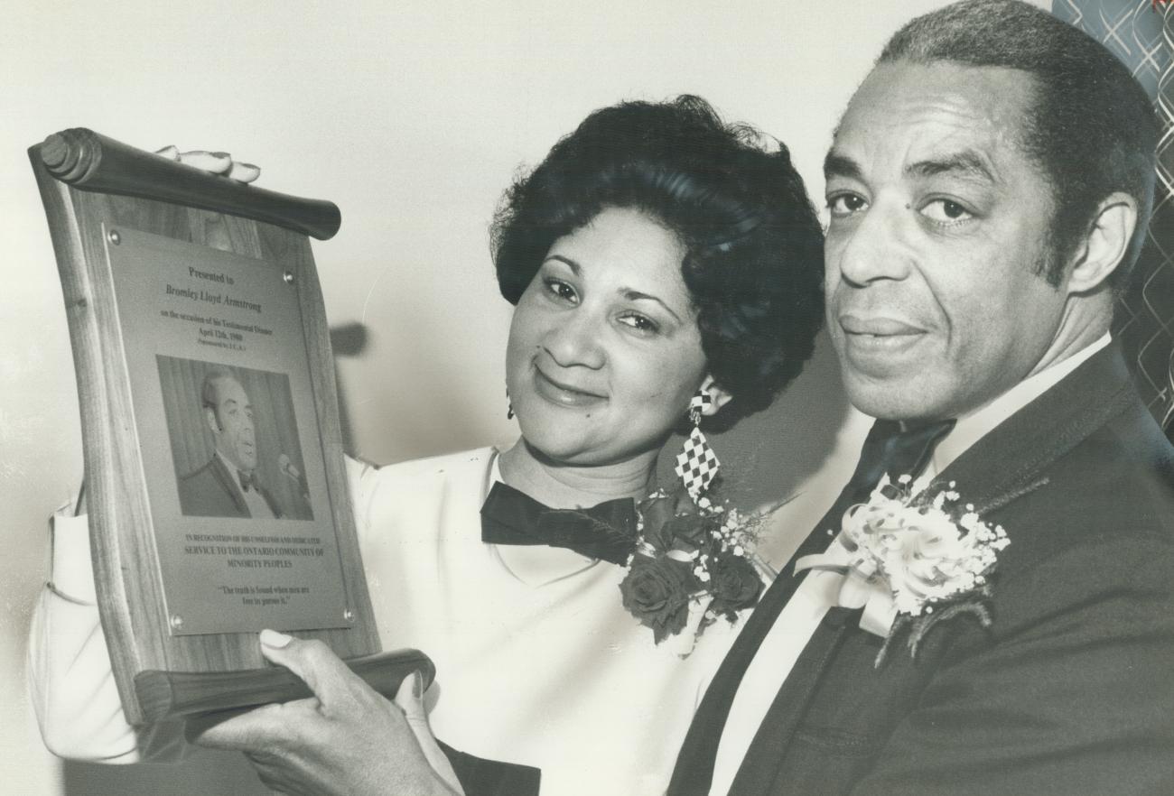 Bromley Armstrong and a woman holding a plaque with text and a photo of Bromley Armstrong on it.