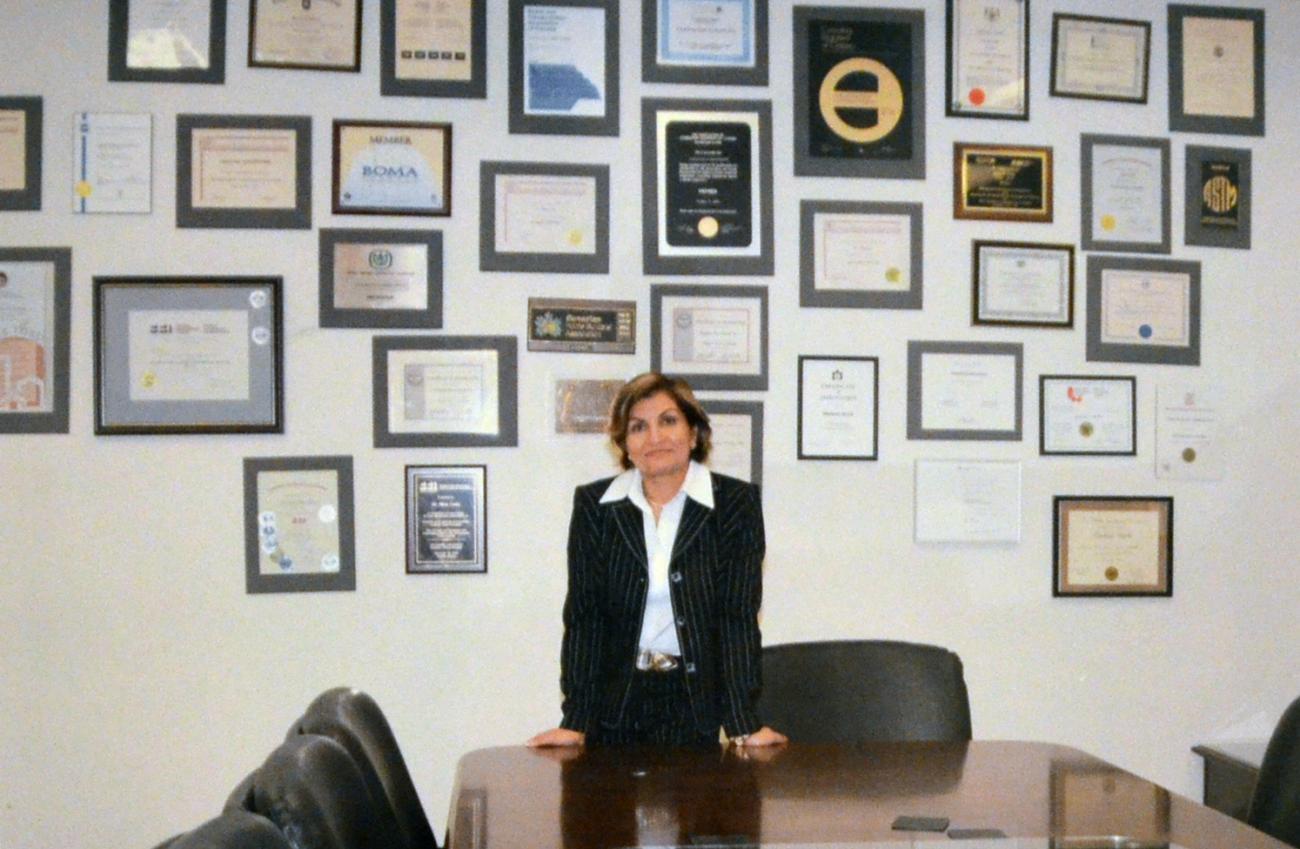 Gina Cody standing in front of a wall of framed certificates and other texts, some with logos,