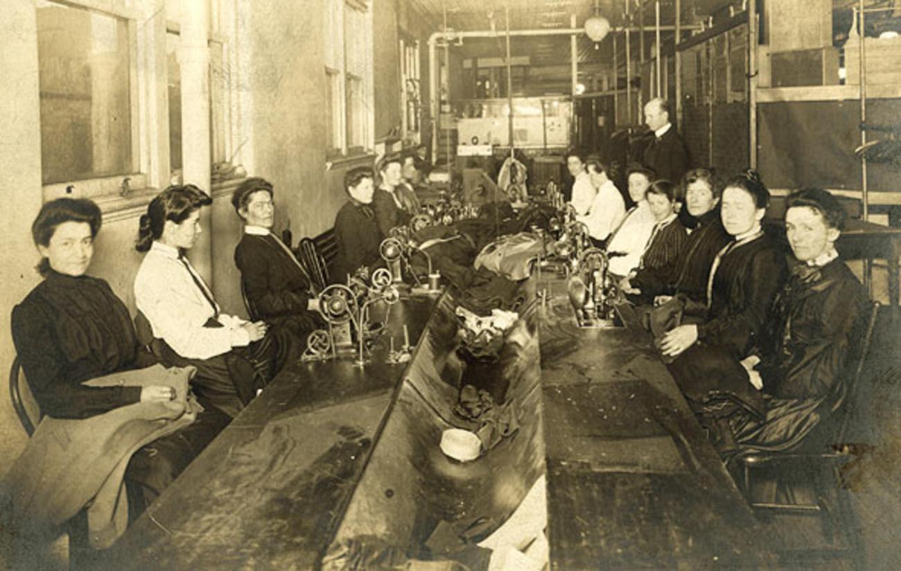 sepia photo of two rows of women at sewing machines.
