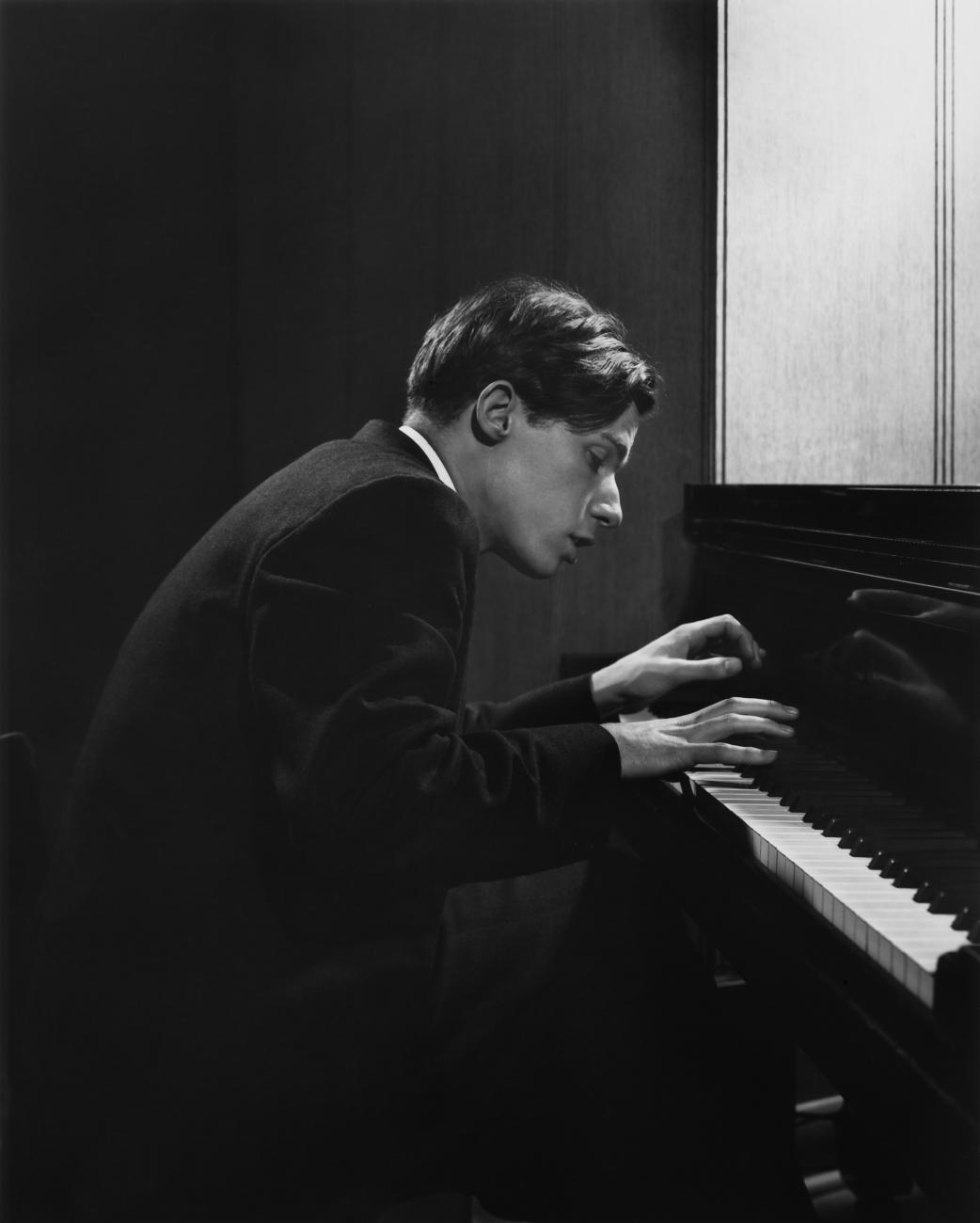 Black and white photo of a man playing a piano.