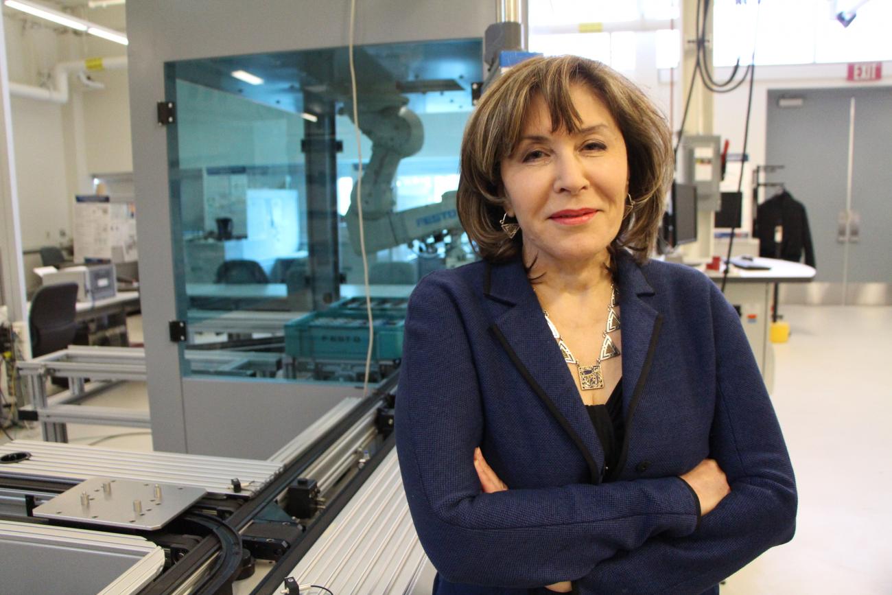 Hoda ElMaraghy in dark blue jacket standing in a science lab.