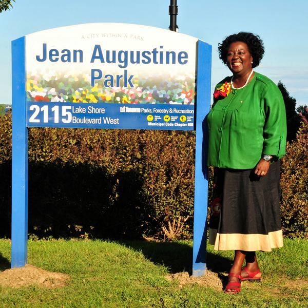 Jean Augustine stands by a sign for Jean Augustine Park.