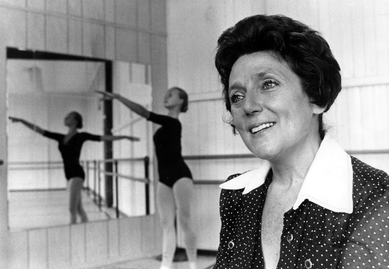portrait of Ludmilla Chiriaeff in a dance studio with female dancer in the background.
